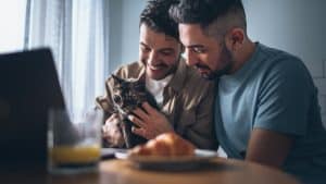Happy Gay Couple in Love Having Healthy Breakfast and Playing with their pet cat