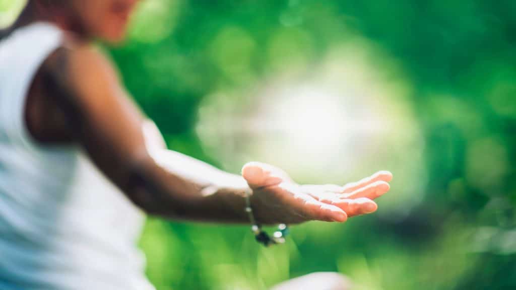 Woman walking through green space, holding hand out