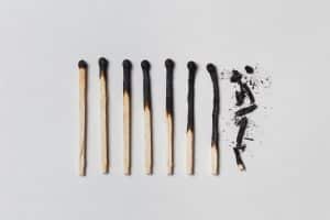 A row of burnt matches, from left to right, from almost a whole match to a completely burnt match to the dust. White background, flat lay.