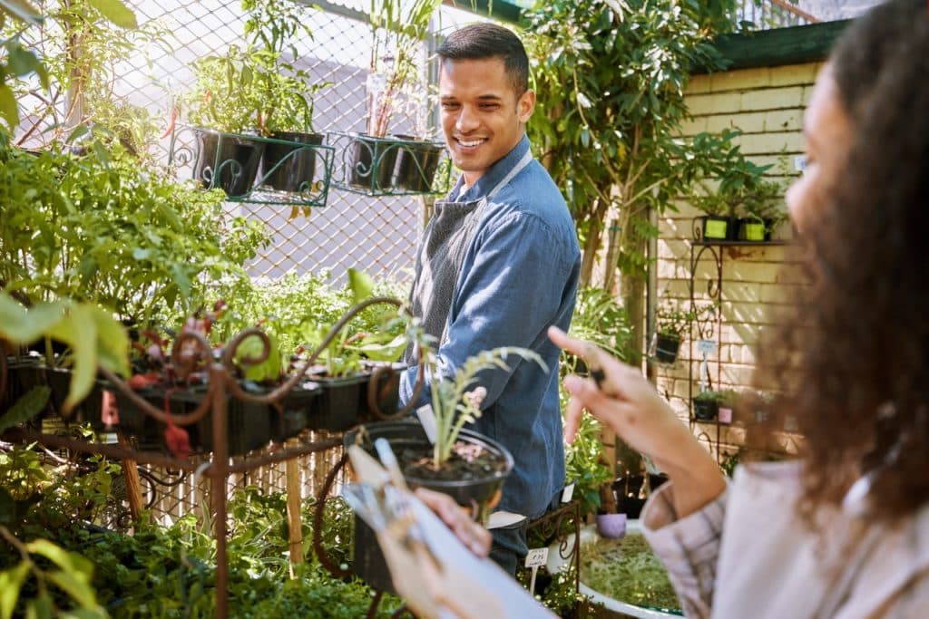 A couple checking in the plants in a greenhouse together at home.