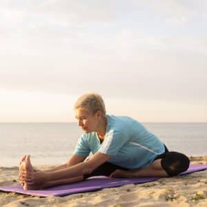 front-view-mature-woman-doing-yoga-beach