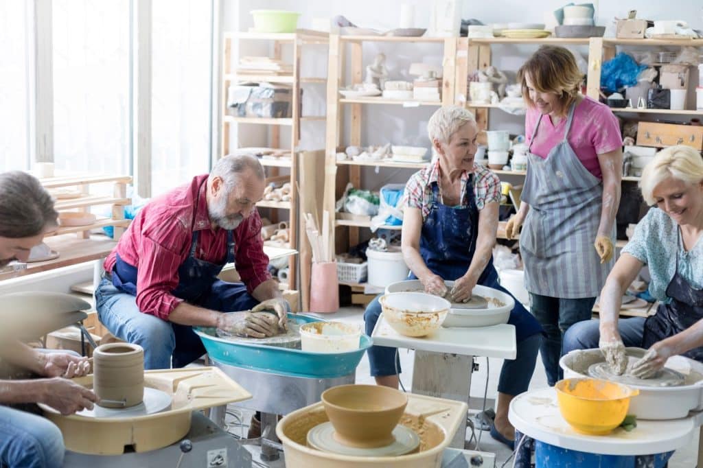 Mature students using pottery wheels in studio