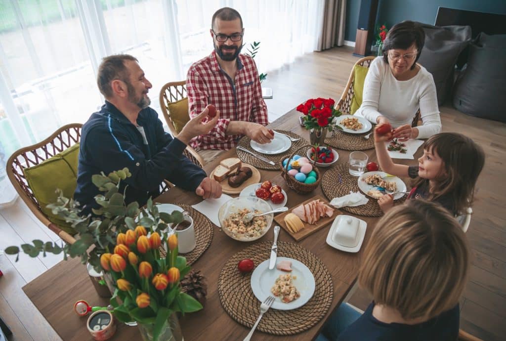 Candid family gathering together at home for celebrating and eating Easter breakfast
