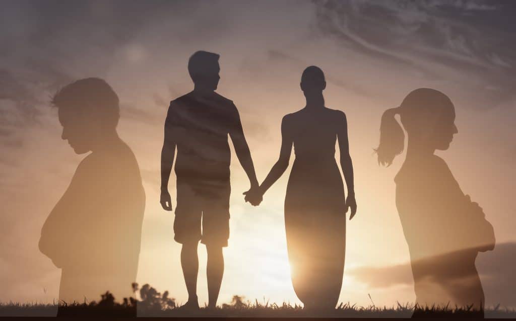 Man woman couple in a relationship stood holding hands, transparent versions of themselves facing away from each other.